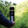 a person holding a thermos outdoors