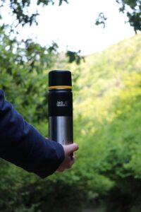 a person holding a thermos outdoors