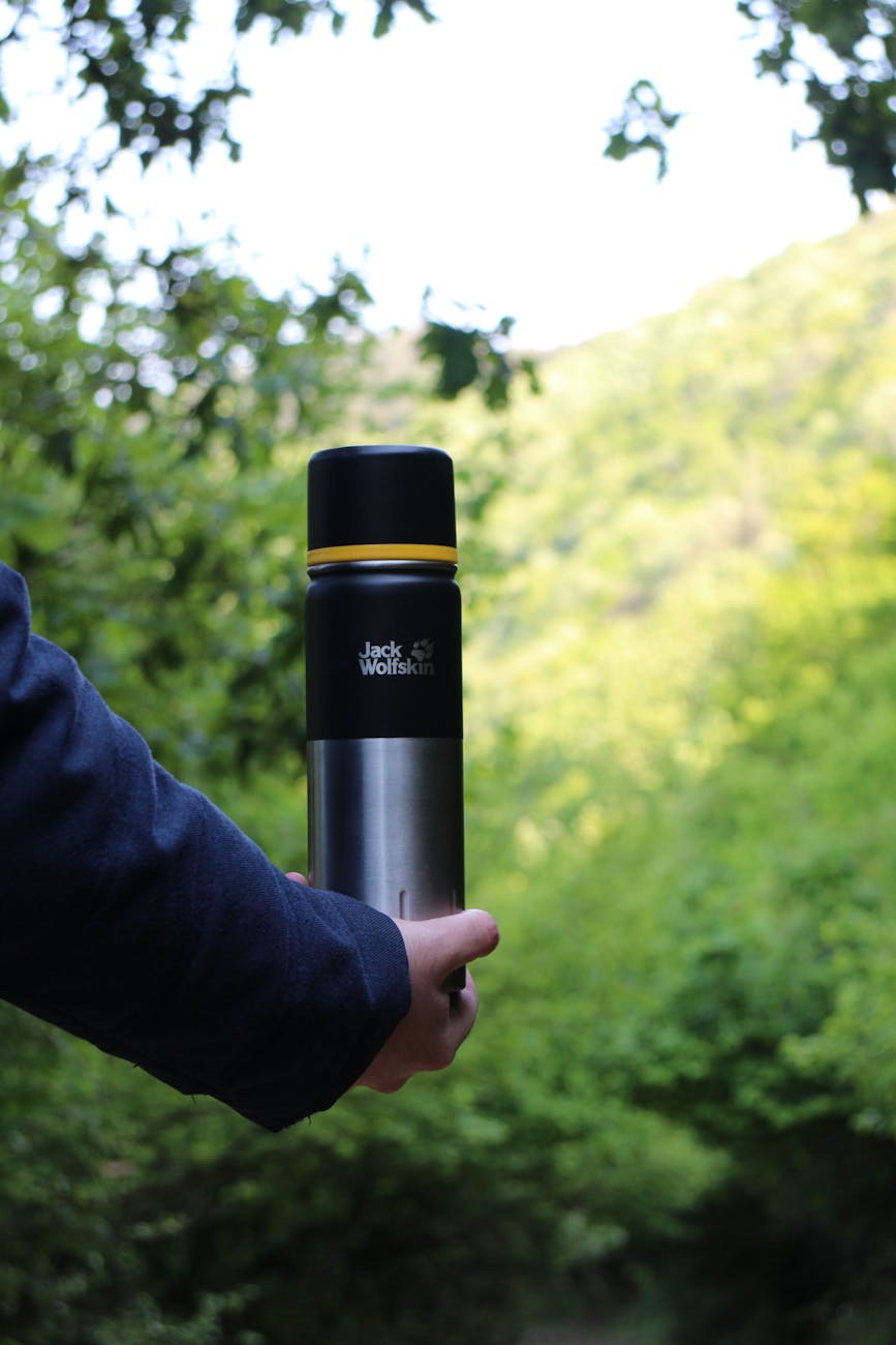 a person holding a thermos outdoors